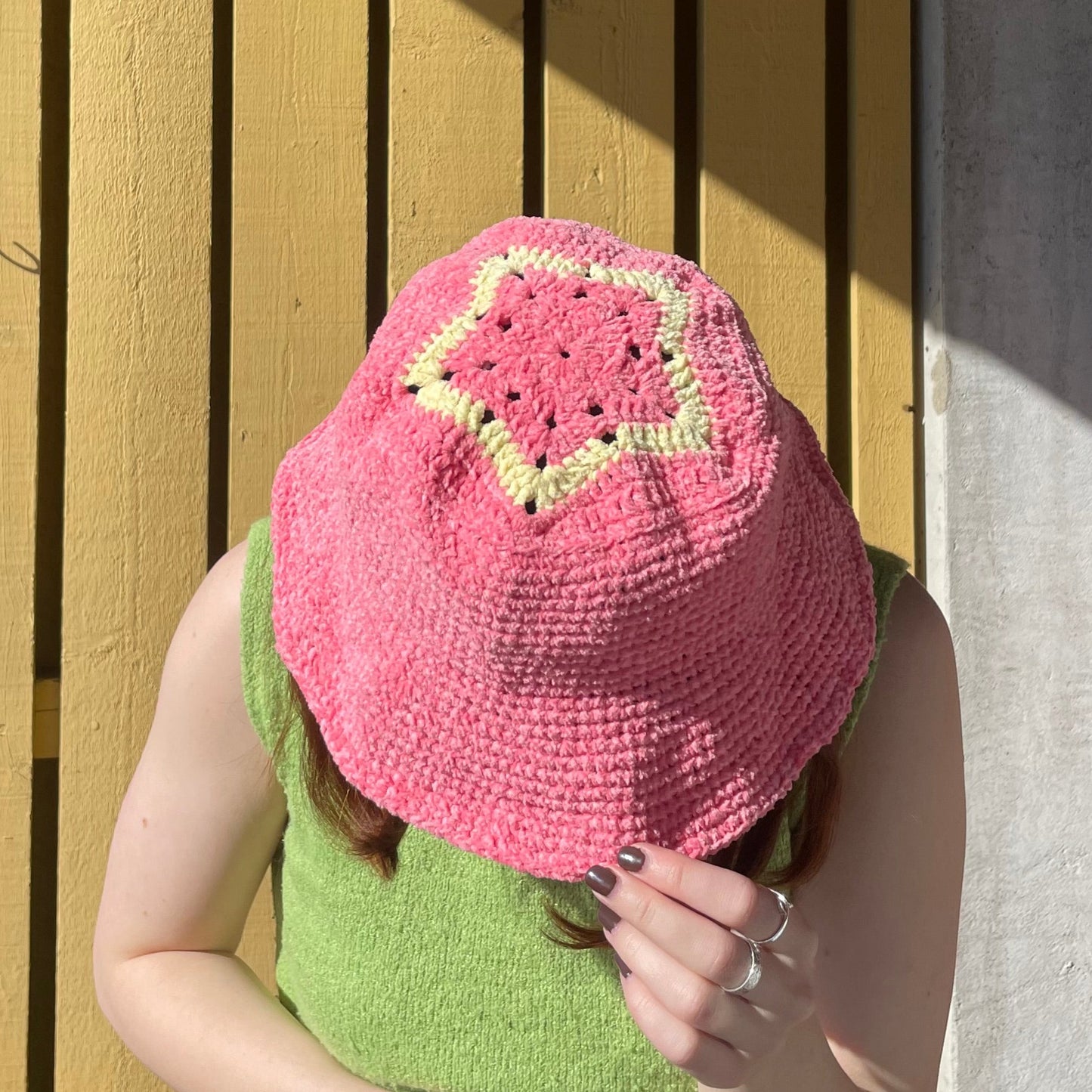 Virkad bucket hat i bubbelgumsrosa. På toppen finns en speciell detalj, en stjärna i en ljusare gul färg.
