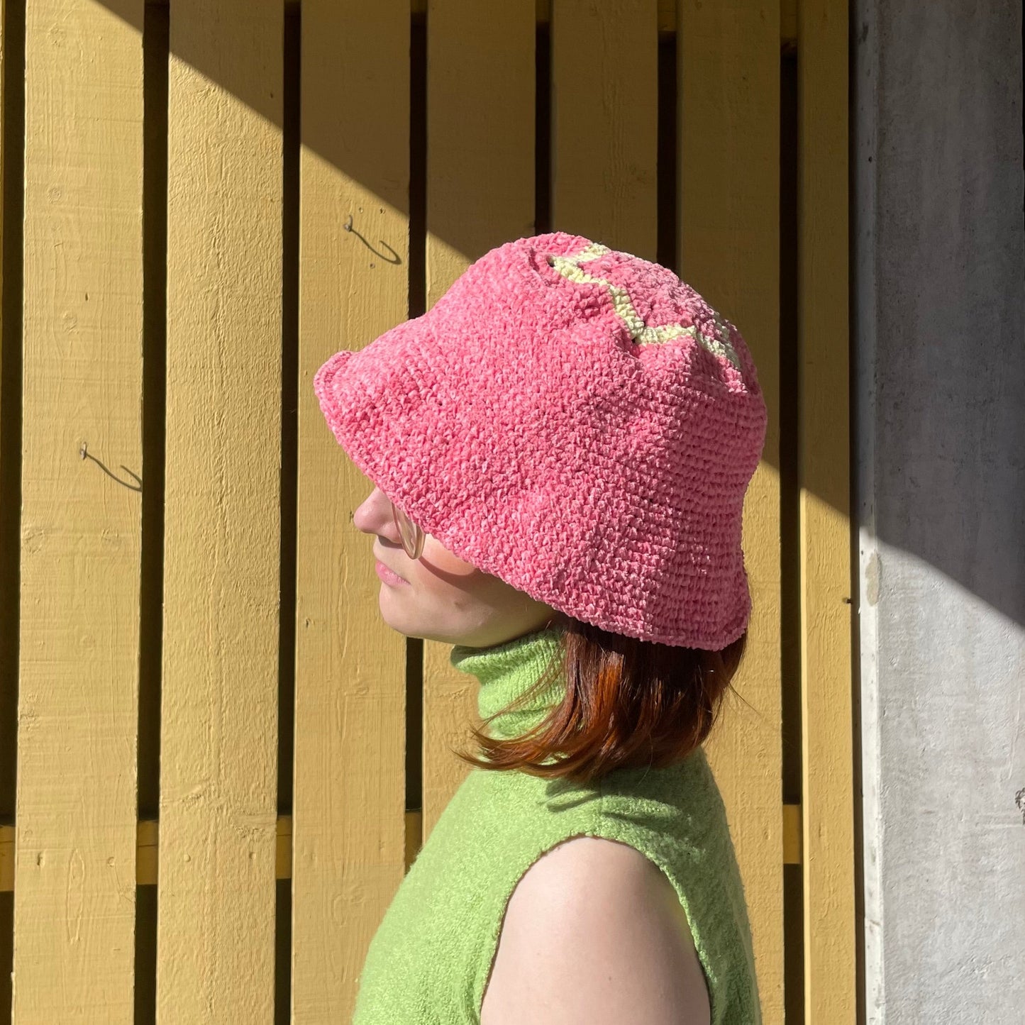 Sidan av en virkad rosa hatt, i bucket hat-modell. På ovansidan av den handgjorda hatten finns en gul stjärna som ger den ett unikt utseende.