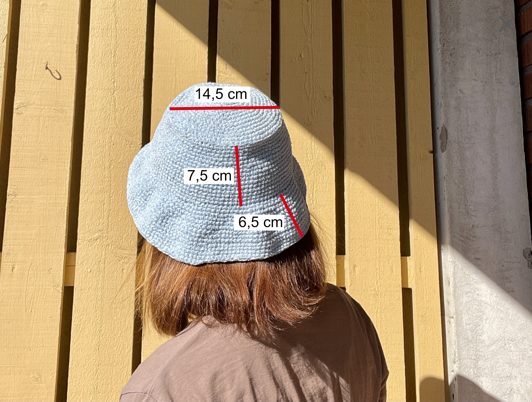 En bild som visar att måtten på hatten är 14.5 cm i diameter på ovandelen, 7.5 cm hög på kanten och 6.5 cm bred på skärmen.